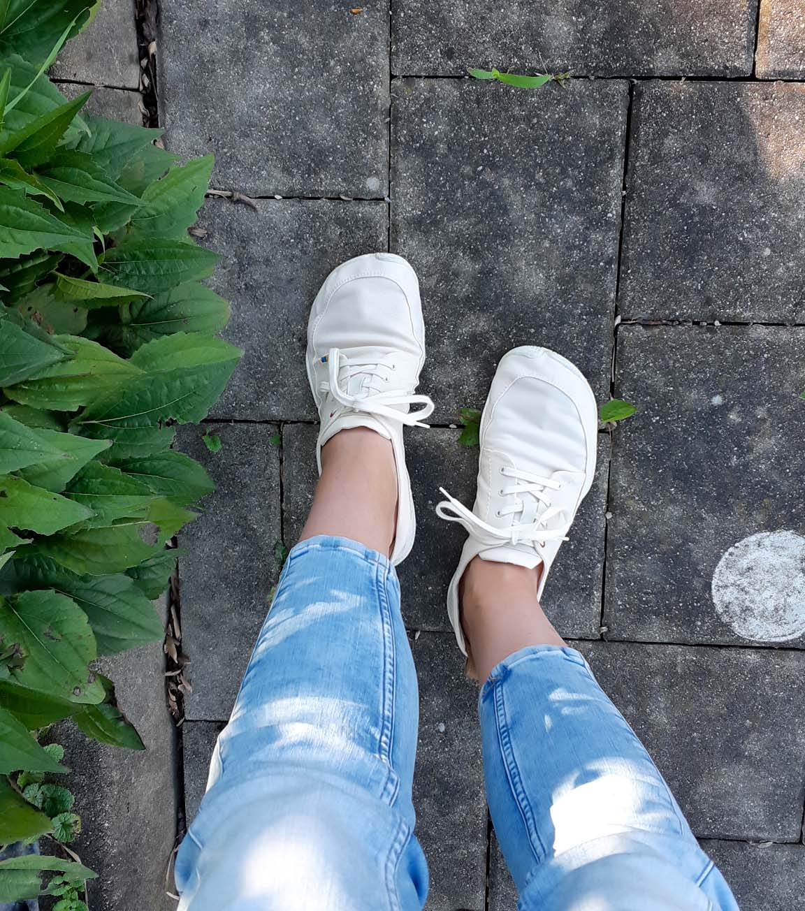 White sneakers worn outdoors on a stone path