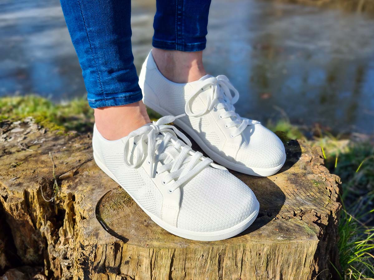 White sneakers worn outdoors on a tree stump