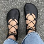 Black lace-up barefoot ballet flats with wide toe box worn outdoors
