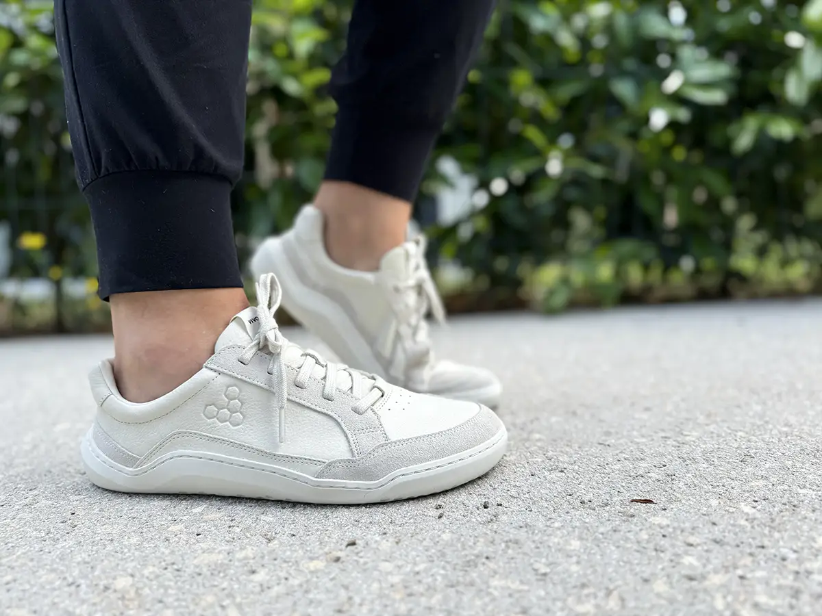 Light-colored barefoot sneakers worn outdoors on pavement