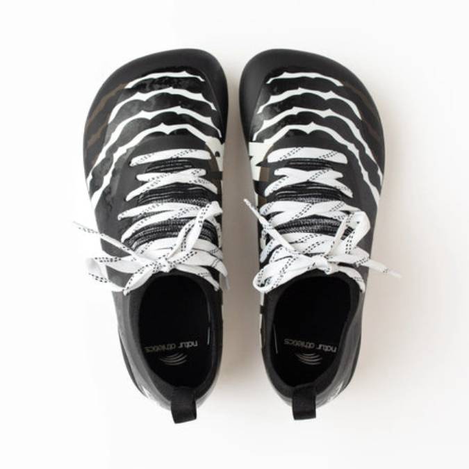 Top view of Natur Athletics wide toe box cleats in black with white zebra stripe design and white laces.