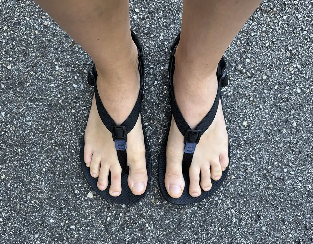 Top view of Shamma Numa barefoot sandals with soft toe post and front strap, worn on feet standing on asphalt
