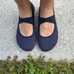 Dark blue barefoot ballet flats with cross strap worn outdoors on pavement
