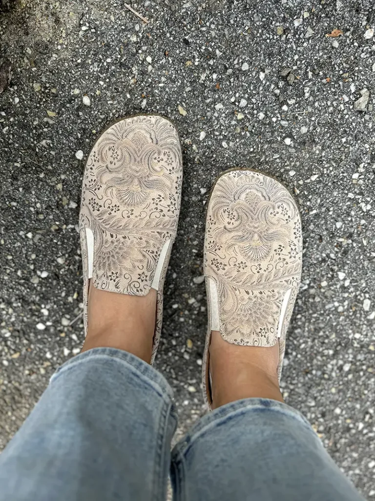 Peerko Trim barefoot loafers in beige floral leather, featuring wide toe box and flexible minimalist sole, worn with jeans on pavement.
