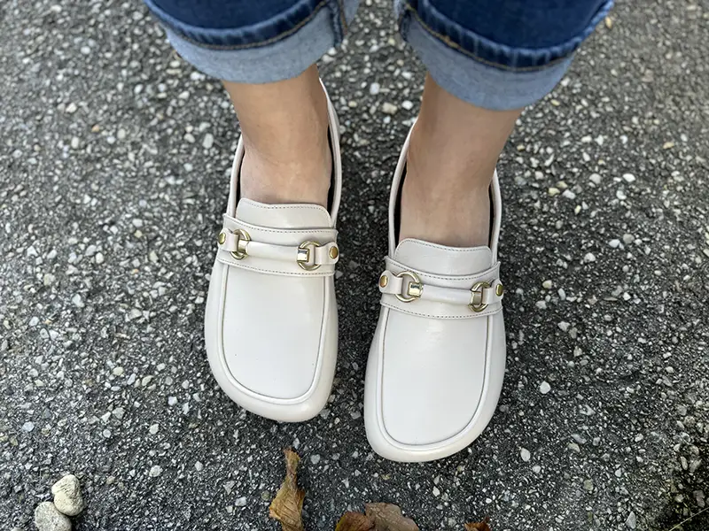 Shapen Versa beige barefoot loafers with wide toe box and minimalist sole, worn outdoors on pavement.
