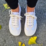 Pair of white barefoot sneakers with wide toe box shown outdoors.