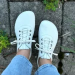 Minimalist white barefoot sneakers with laces on outdoor path.