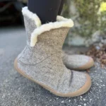 Gray felt barefoot winter boots with wool lining shown from the side outdoors.