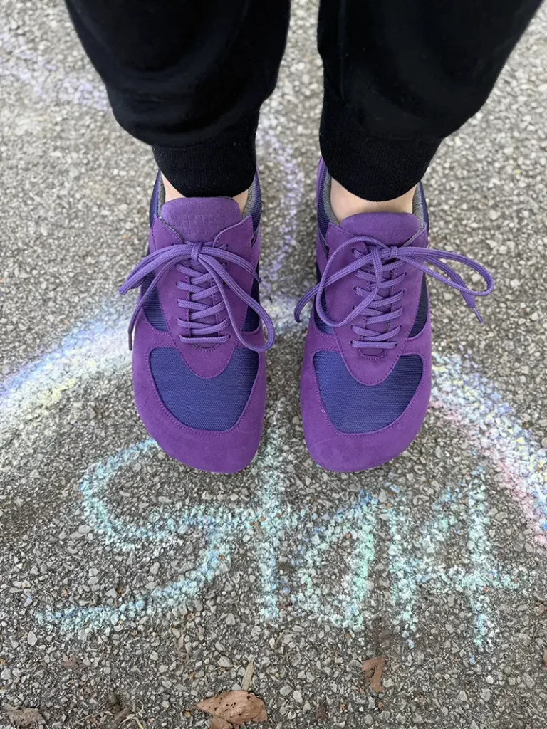 Purple barefoot sneakers worn outdoors on pavement