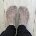 Person wearing thick knit socks indoors, viewed from above