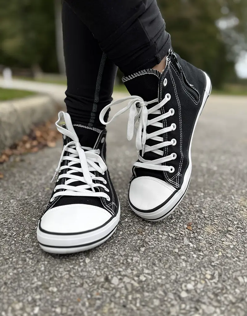 Black barefoot sneakers with white sole worn outdoors