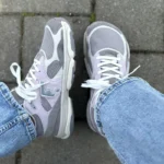 Grey barefoot sneakers worn with jeans outdoors