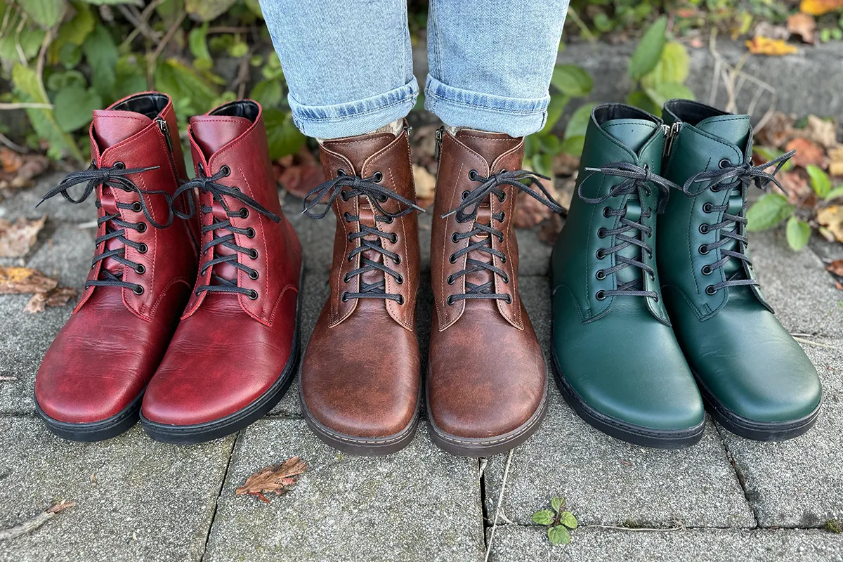 Red, brown and teal Peerko barefoot combat boots displayed side by side, with the brown pair worn with cuffed jeans.